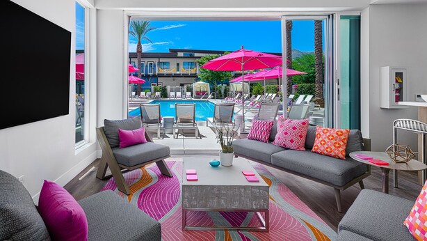 A modern living room with grey sofas, a coffee table, and a pool view. - The Paloma Resort (Cathedral City)