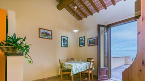 Un coin repas avec une table et des chaises, une plante suspendue et des tableaux encadrés au mur.
