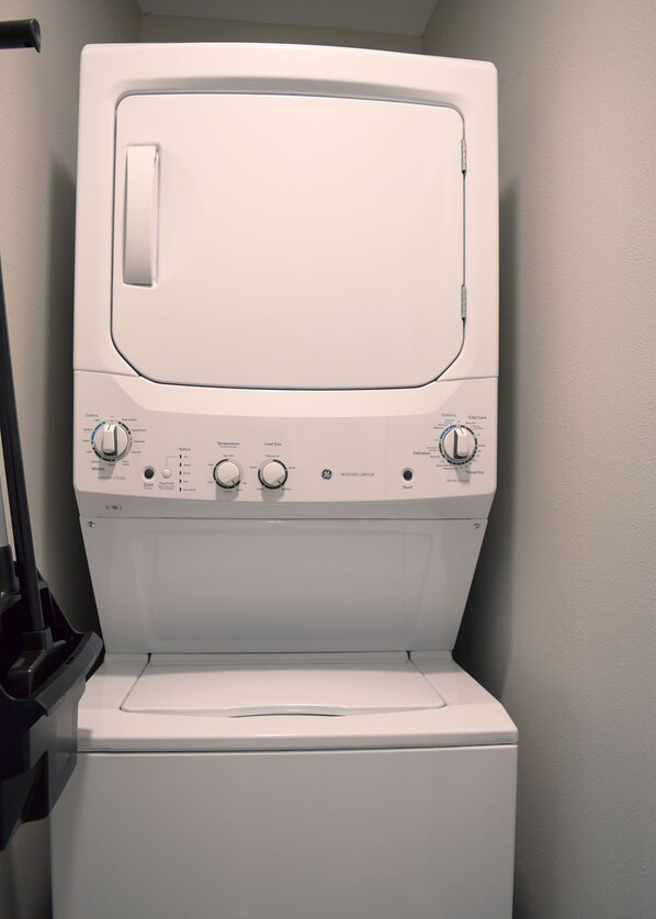 A front view of a white washer and dryer unit with control knobs and buttons for various settings.