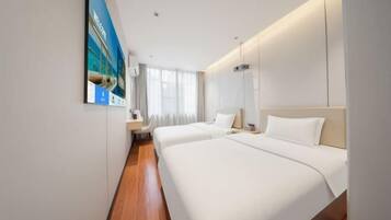 Quarto de hotel com duas camas, uma janela grande e um quadro na parede.