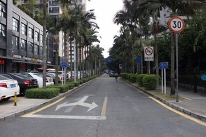Una calle urbana con automóviles estacionados, una señal de límite de velocidad y flechas direccionales en la carretera.