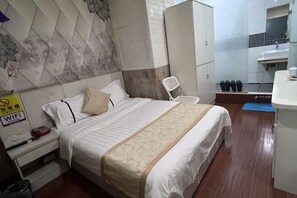 A hotel room with a bed, a nightstand, a wardrobe, a bathroom with a sink and mirror, and a blue mat on the floor. - Shenzhen Guihua Hotel (Fubao Subway Station Branch) (Shenzhen)