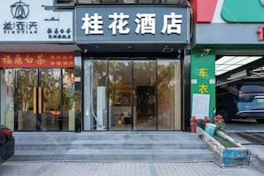 A hotel entrance with a glass facade, steps leading up to the door, and a car parked outside. - Shenzhen Guihua Hotel (Fubao Subway Station Branch) (Shenzhen)