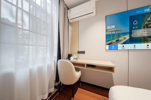 A hotel room with a desk, chair, TV, air conditioning unit, and a window with curtains. - Shenzhen Guihua Hotel (Fubao Subway Station Branch) (Shenzhen)