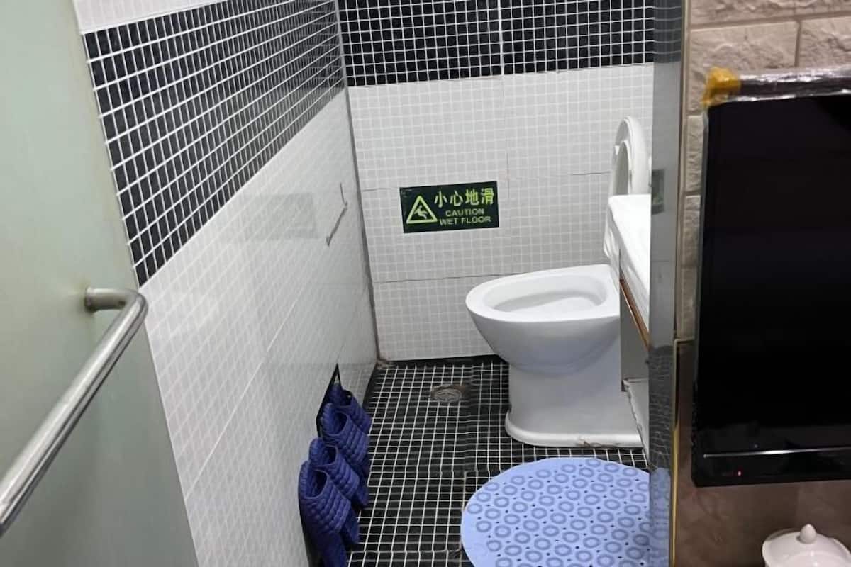 A bathroom with a wet floor sign, a toilet, a sink, and a shower area.