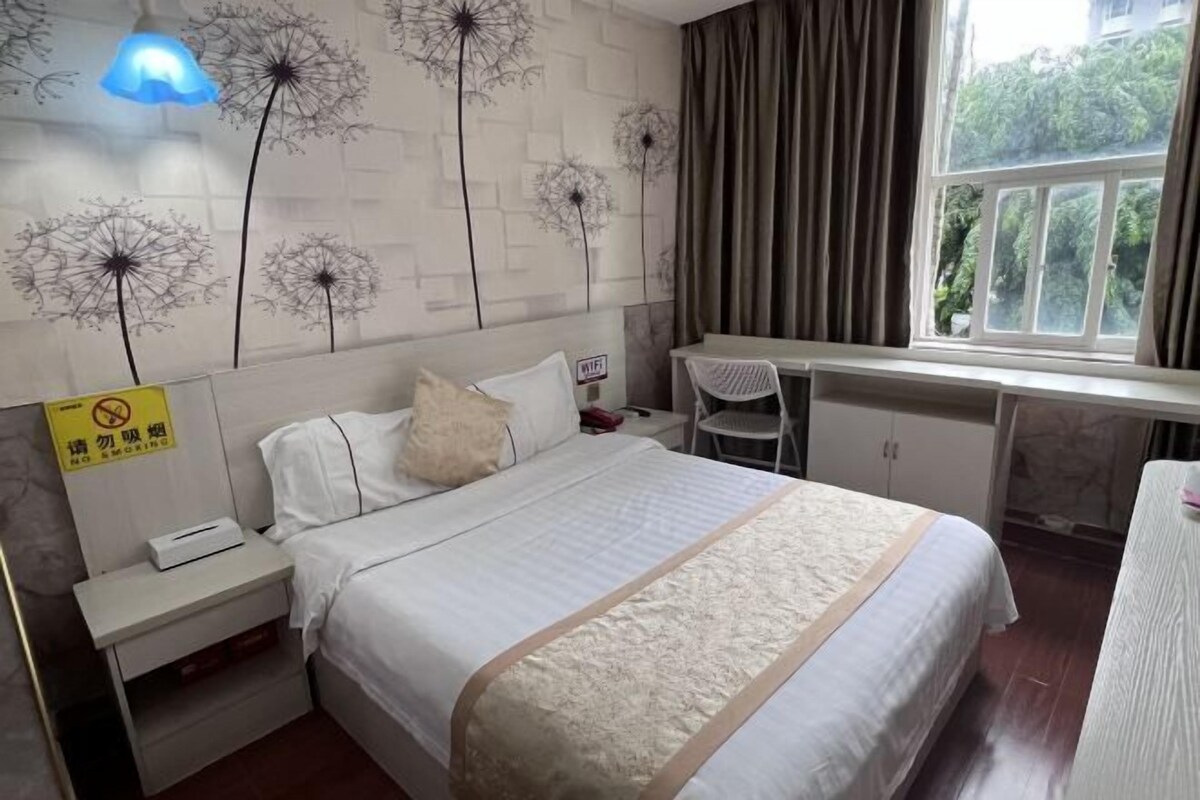 A hotel room with a bed, a desk, and a window.