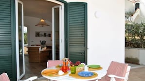 Une terrasse avec une table ronde, des chaises et un coin repas.