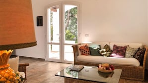 Un salon comprenant un canapé, une table basse en verre, une lampe et une porte donnant sur un espace extérieur.