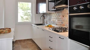 Une cuisine moderne avec des armoires blanches, une cuisinière noire et un pare-feu décoré.