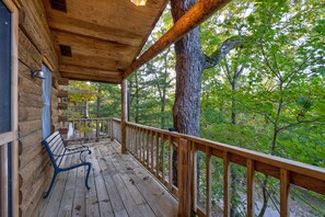 A wooden cabin with a covered porch, a bench, and a view of a forested area. - Newly Renovated! Cozy Lakefront Cabin on Table Rock - Timbers 6 (Shell Knob)