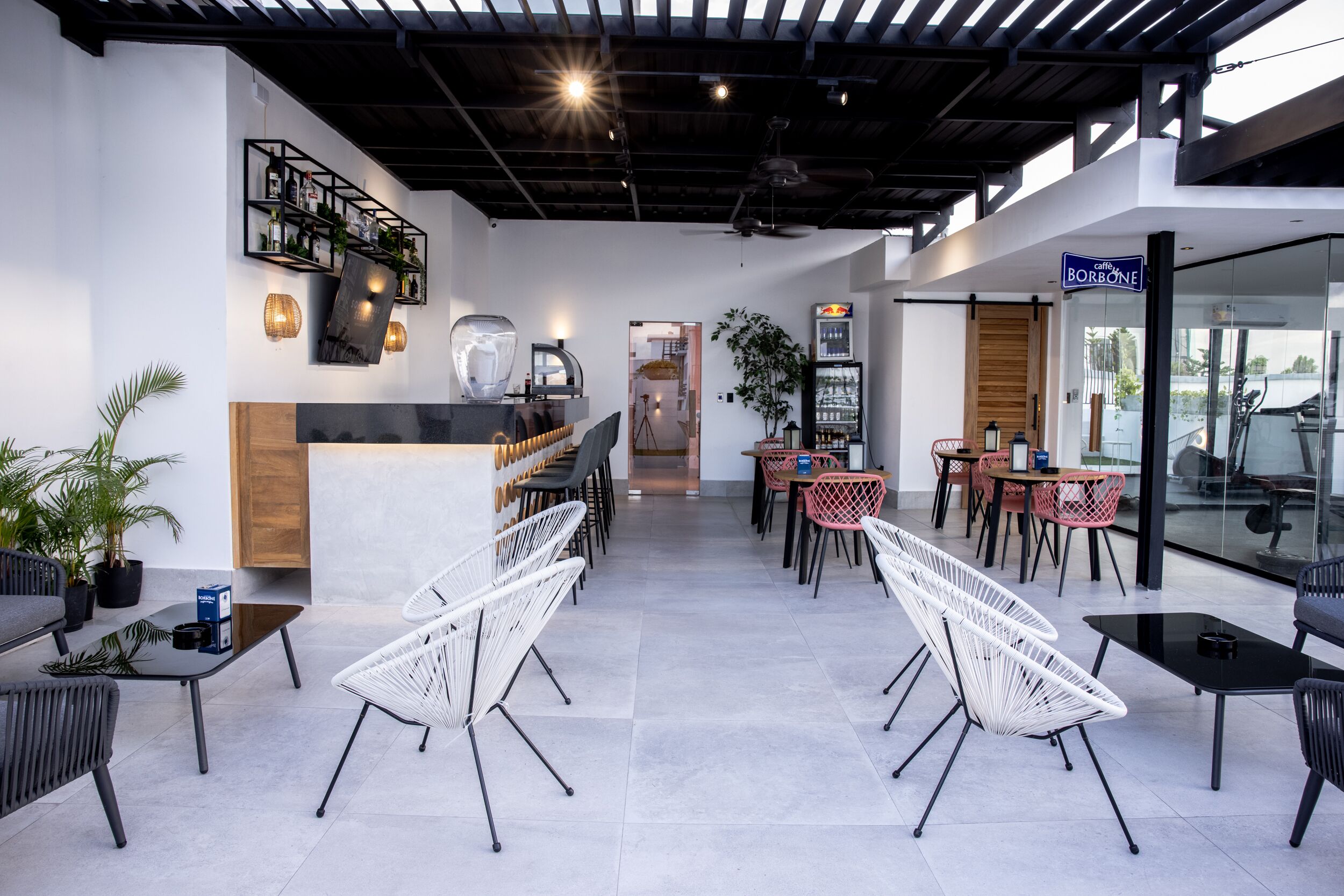 Moderni kahvila, jossa on valkoiset tuolit, baarialue ja kyltti, jossa lukee ”Café Borbone”.