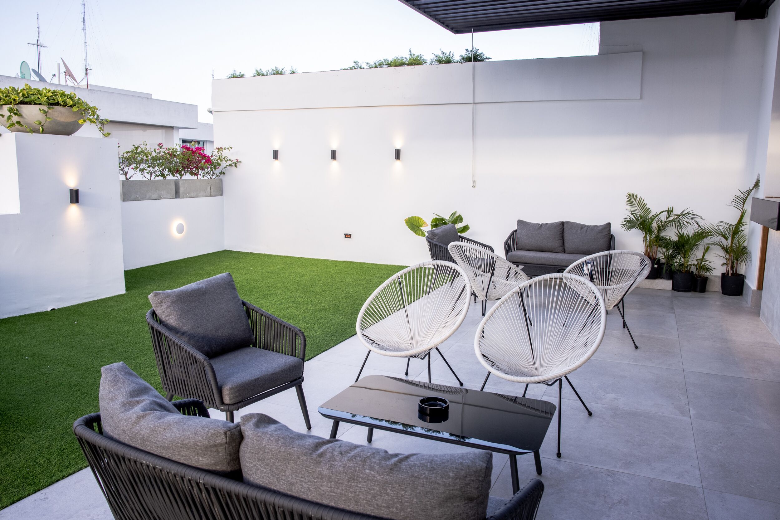 A modern outdoor patio with wicker furniture, a small table, and potted plants.
