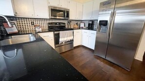 Una cocina moderna con armarios blancos, un refrigerador de acero inoxidable, un microondas y una estufa.