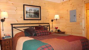 Un dormitorio con paneles de madera, una cama, dos mesitas de noche y un cuadro en la pared.