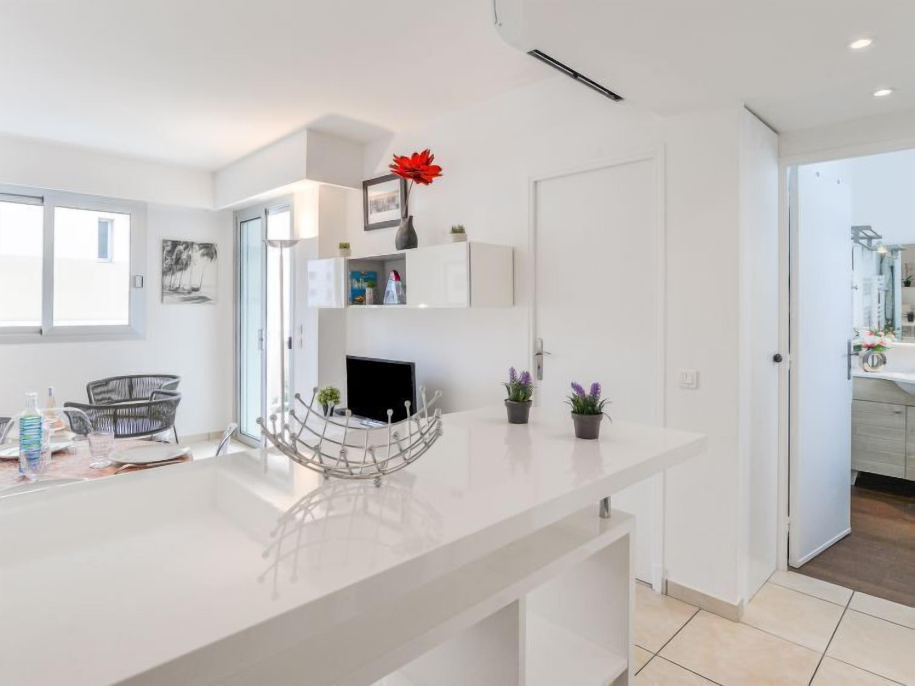 Une cuisine moderne avec un plan de travail blanc, un four encastré et un coin repas comprenant une chaise et une table.