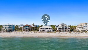 A beachfront property with multiple houses, a beach in the foreground, and a clear blue sky. - OMG by the Sea: Beachfront in Plantation, Community Pool, One level (St. George Island)