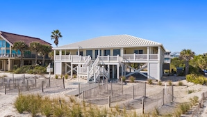 A beachfront house with a two-story structure, a balcony, and a staircase leading to the upper level. - OMG by the Sea: Beachfront in Plantation, Community Pool, One level (St. George Island)