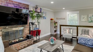 A living room with a fireplace, a television, and a coffee table. - Spacious home with King bed - mins to Stadiums (Independence)