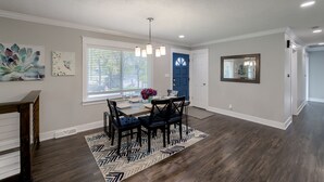 A dining area with a table set for four, a blue door, and a mirror on the wall. - Spacious home with King bed - mins to Stadiums (Independence)