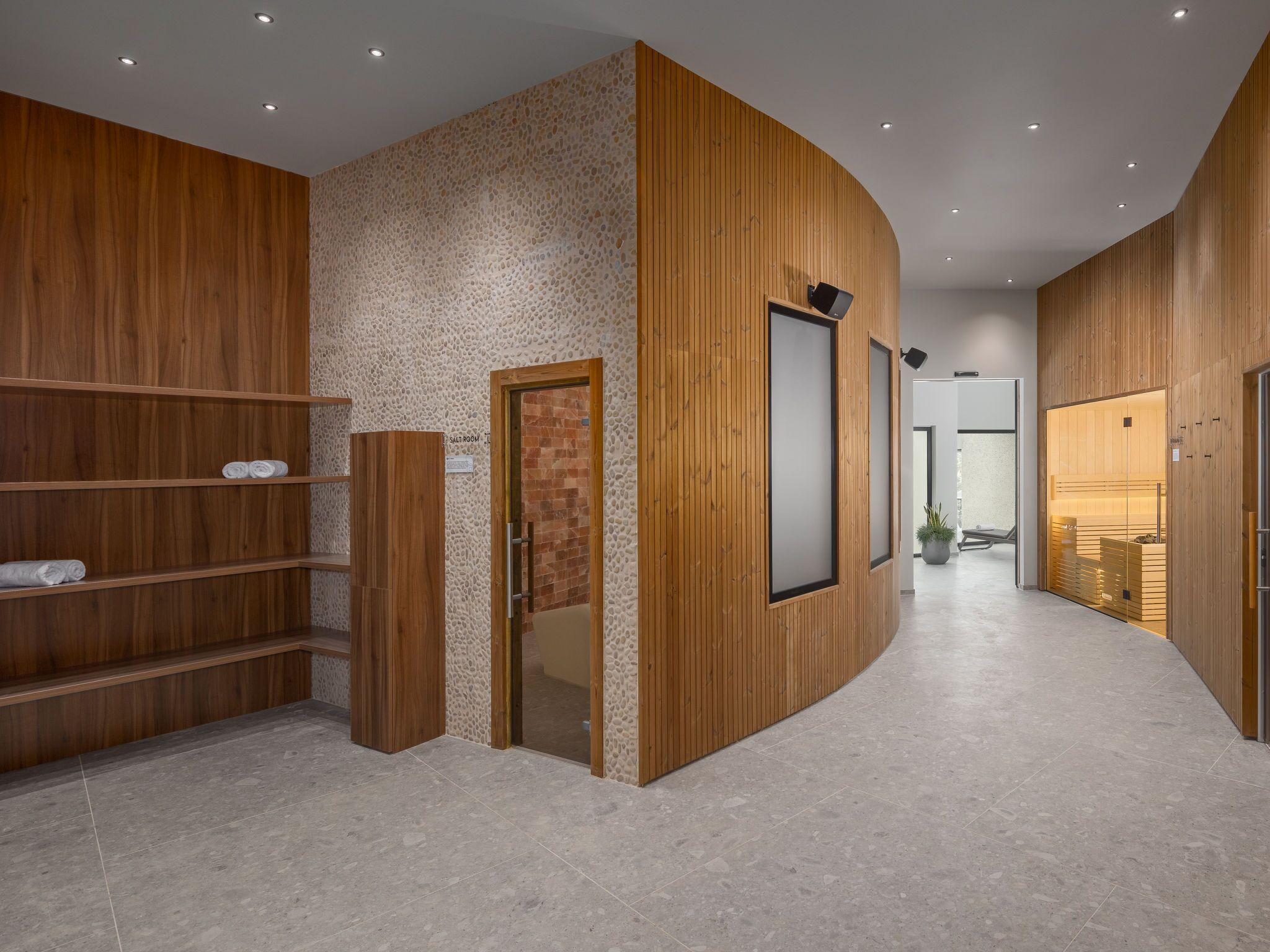 A modern hotel lobby with wooden paneling, a salt room, and a visible bathroom.