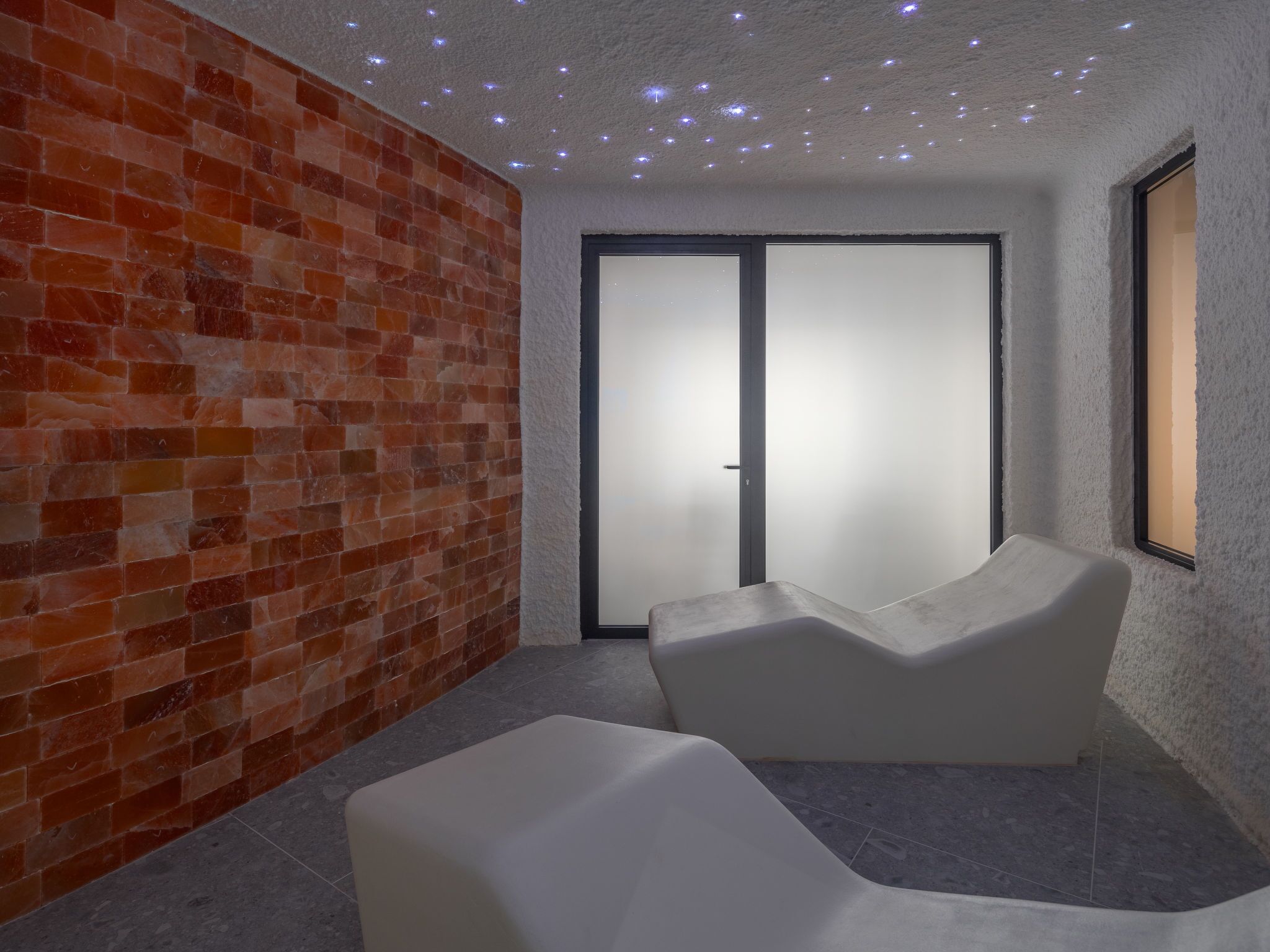 A modern room with a brick wall, a sliding door, and a white, curved bench.