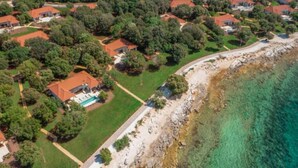 Et kystnært boligområde med huse, en swimmingpool og en klippefyldt kystlinje.