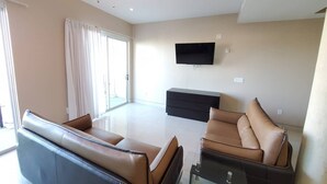 Una sala de estar moderna con un sofá, una mesa de centro y un televisor de pantalla plana montado en la pared.