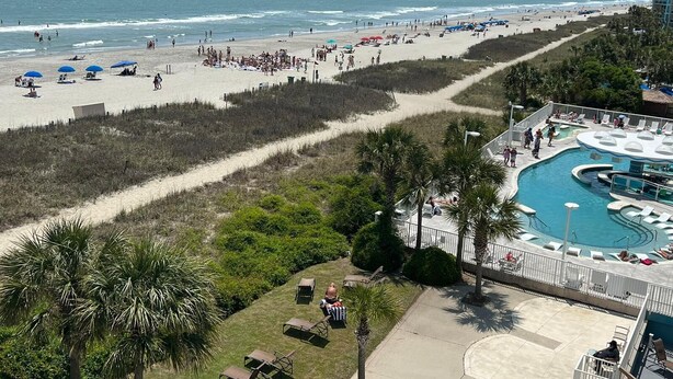 Un complejo turístico en la playa con piscina, zona de playa y palmeras.
