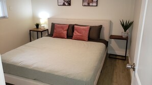 Une chambre à coucher bien rangée, avec un grand lit, deux tables de chevet et deux tableaux accrochés au mur.