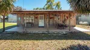 A wooden building with a porch, a door, and a window. - Cypress Cottage in the heart of Steinhatchee! Fenced in yard! (Steinhatchee)