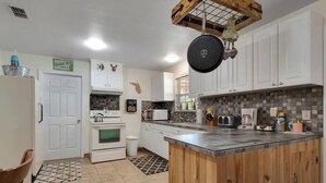 A kitchen with white cabinets, a wooden island, a stove, and a microwave. - Cypress Cottage in the heart of Steinhatchee! Fenced in yard! (Steinhatchee)