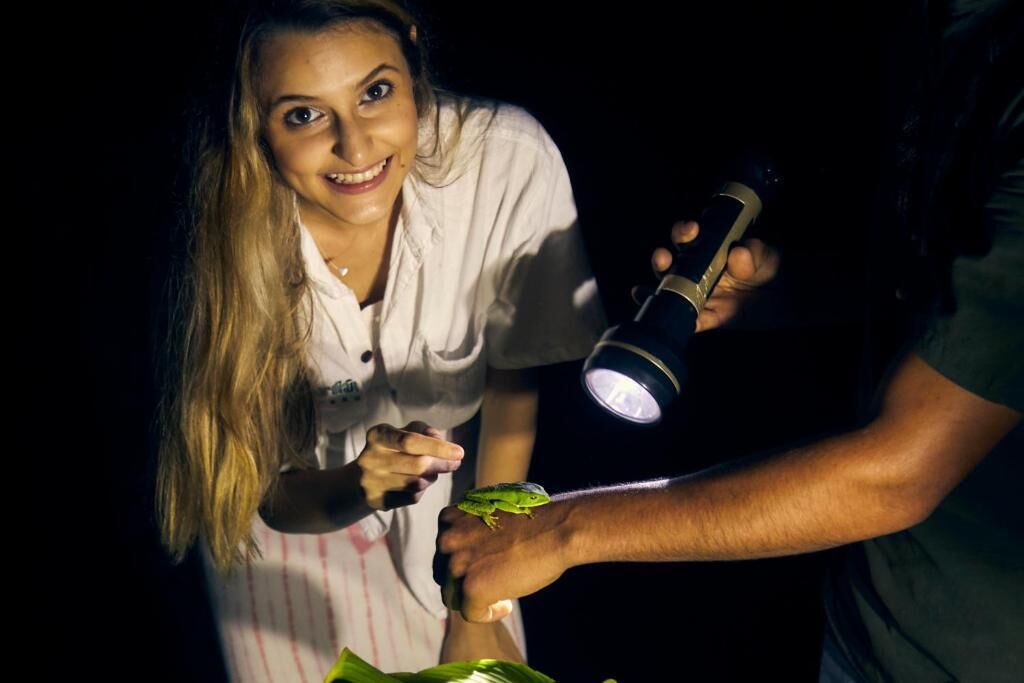 A person holding a flashlight and a frog.