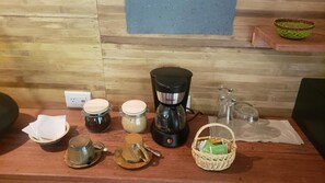 Una encimera de cocina con una cafetera, frascos, una tetera y una cesta.