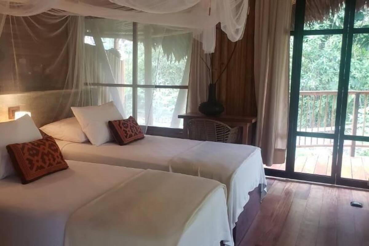 Een kamer met twee bedden, een raam en een ventilator.