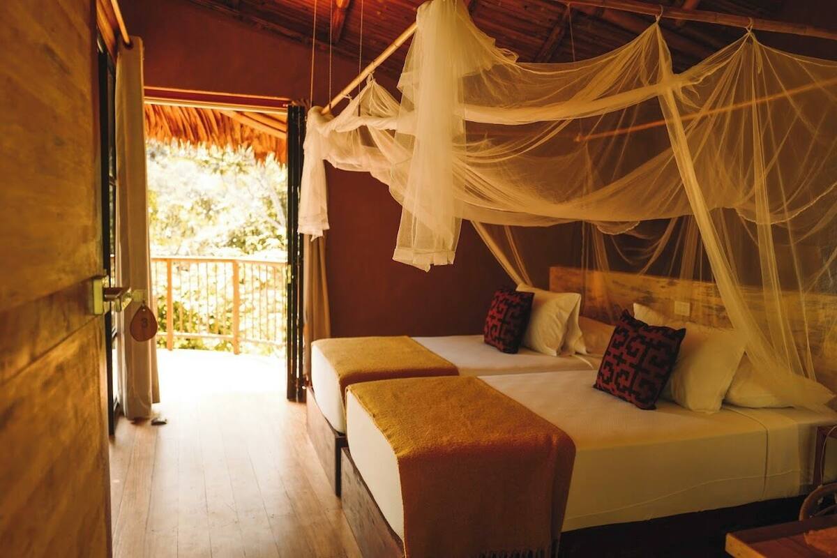 Een kamer met een bed, twee nachtkastjes, een houten vloer en een balkon met uitzicht.