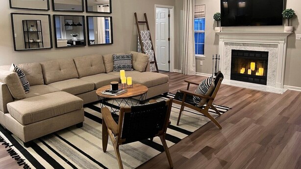 A living room with a sectional sofa, a fireplace, a flat-screen TV, and a chandelier. - Luxurious Grand Park Family Home with Fenced Yard and Game Room! (Westfield)