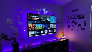 A room with a flat-screen TV mounted on the wall displaying various streaming services. - Luxurious Grand Park Family Home with Fenced Yard and Game Room! (Westfield)
