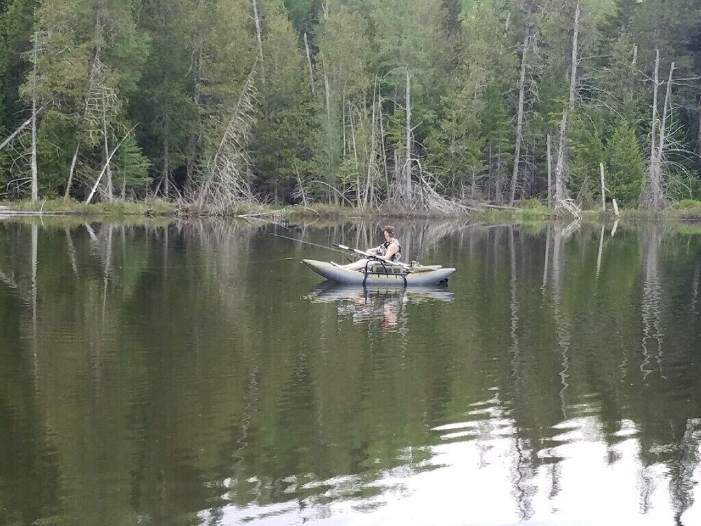 Una persona en una canoa en un lago tranquilo rodeado de árboles.