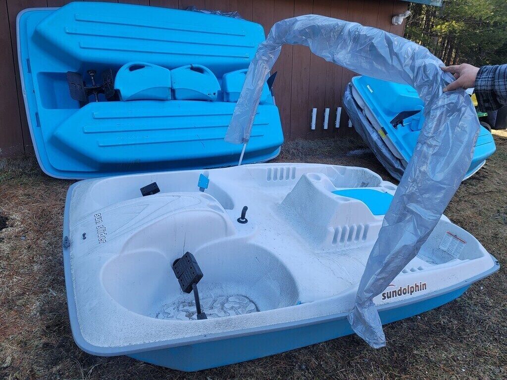 Un bateau gonflable bleu et blanc, sur lequel se trouve une personne qui manipule une bâche en plastique.