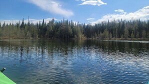 A calm lake with a forested shoreline and a clear sky. - 02) Northwoods Cabin (Stewartstown)