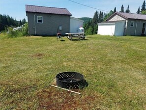 A grassy yard with a metal grill and a white shed in the background.
