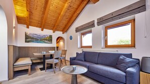 Ein modernes Wohnzimmer mit Holzboden, einem blauen Sofa, einem runden Tisch und einem Essbereich mit Stühlen.