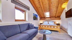 Ein Schlafzimmer mit Holzboden, einem Bett, einem blauen Sofa und einem runden Tisch.