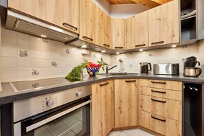 Une cuisine avec des meubles en bois, un four en acier inoxydable, un four à micro-ondes et une machine à café.