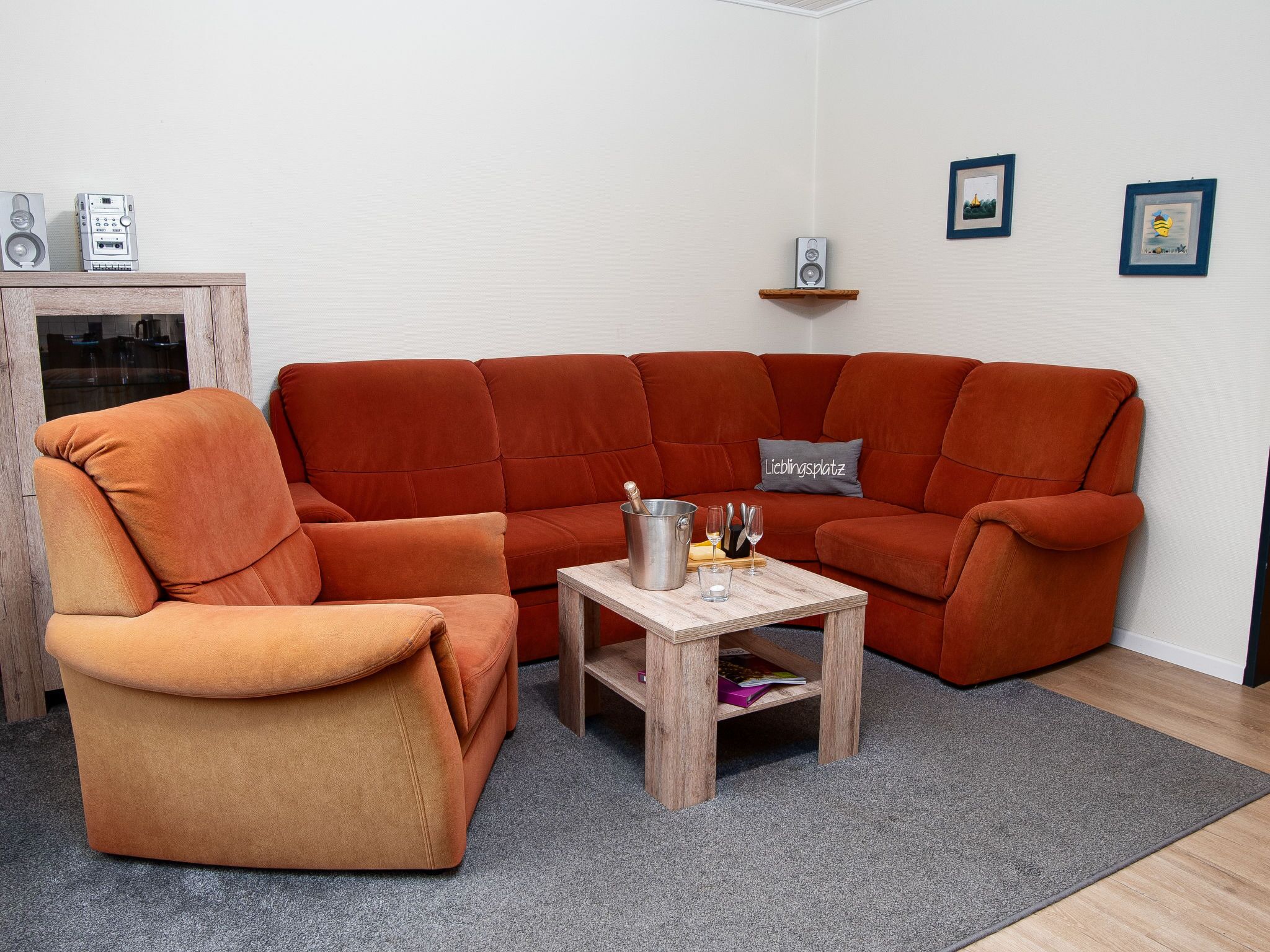 A modern living room with a large orange sofa, a wooden coffee table, and a small side table.