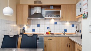 Une cuisine moderne avec des meubles en bois, un plan de travail en granit et un coin repas comprenant deux chaises et une table.