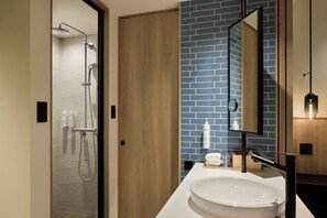 A modern bathroom with a glass shower enclosure, a wooden door, a white sink, and a blue-tiled wall. - Fairfield By Marriott Hokkaido Eniwa (Eniwa)