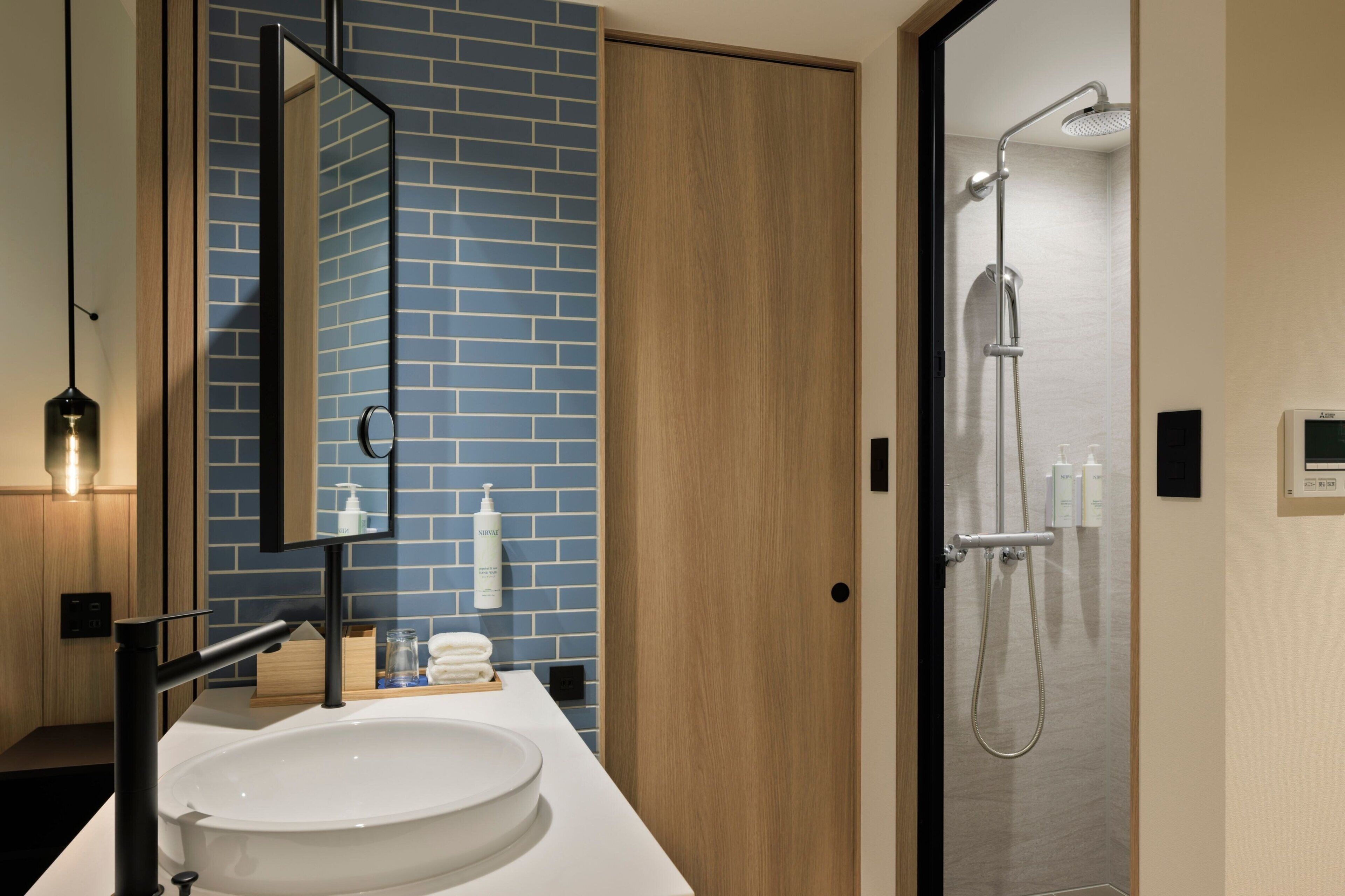 A modern bathroom with a white sink, a mirror, and a shower.