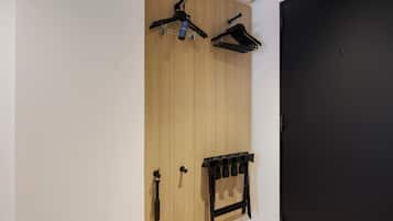 A room with a wooden wardrobe, a black door, and a black coat rack with hooks.