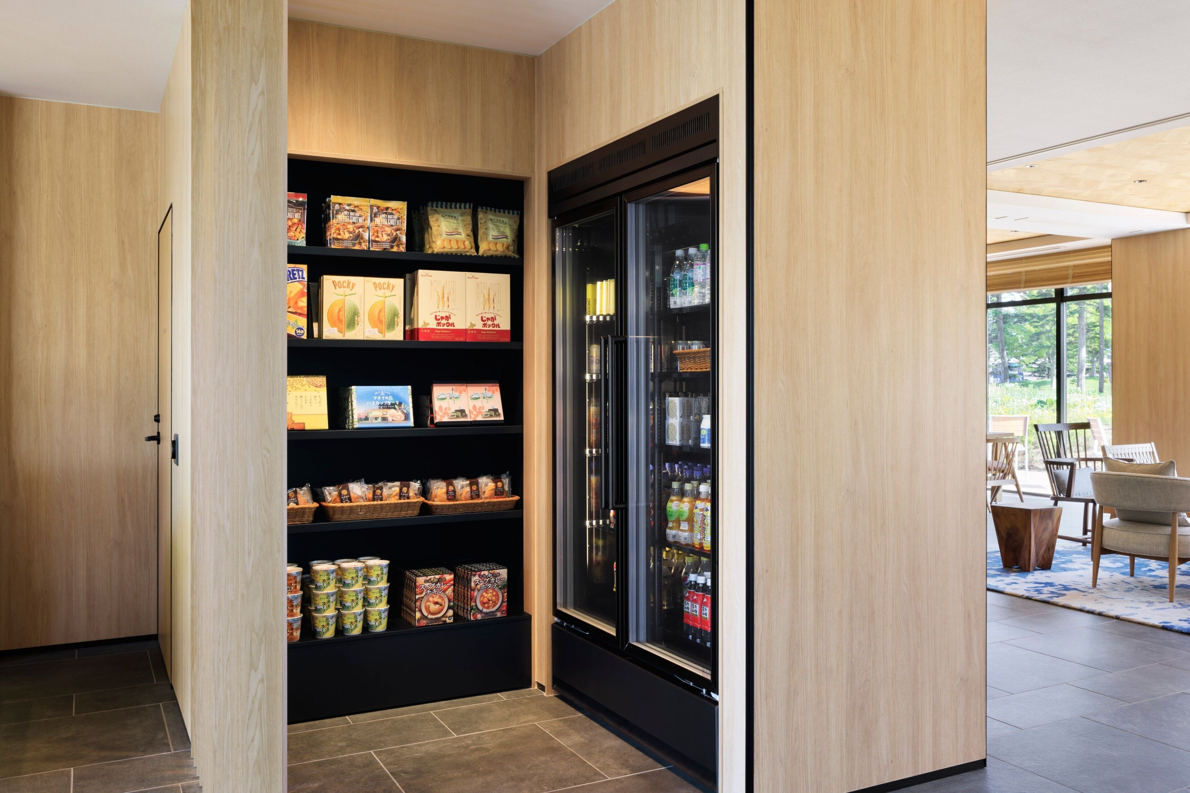 A modern kitchen with wooden cabinetry, a built-in refrigerator, and a variety of food items on shelves.